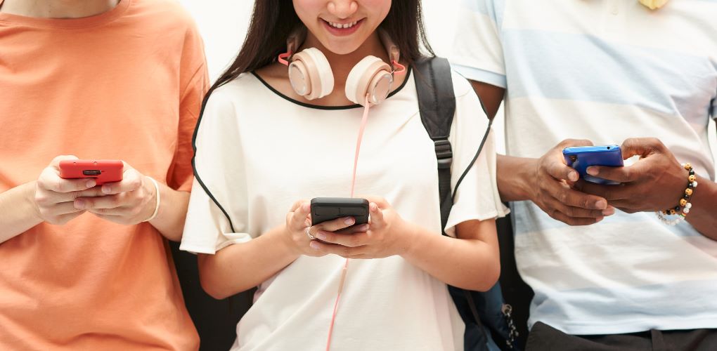 Photograph of school age kids using cellphones