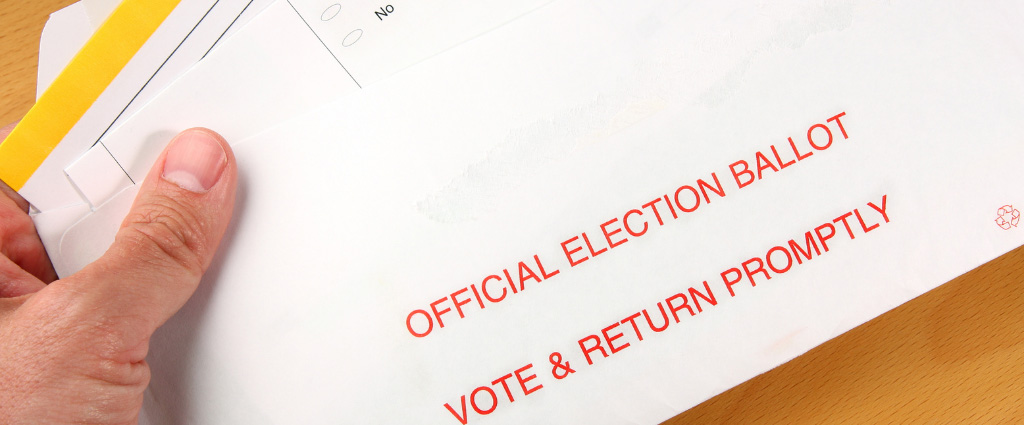 Picture of a hand holding an absentee ballot