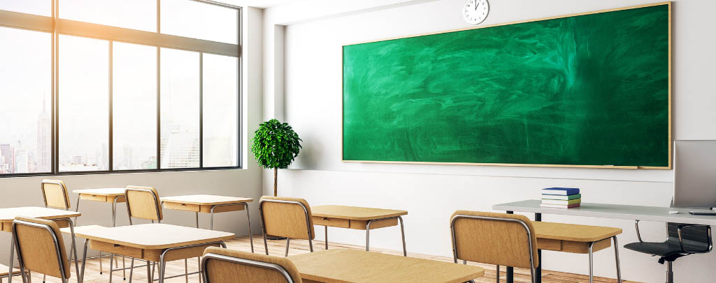 Photo of a bright school room with a green chalkboard