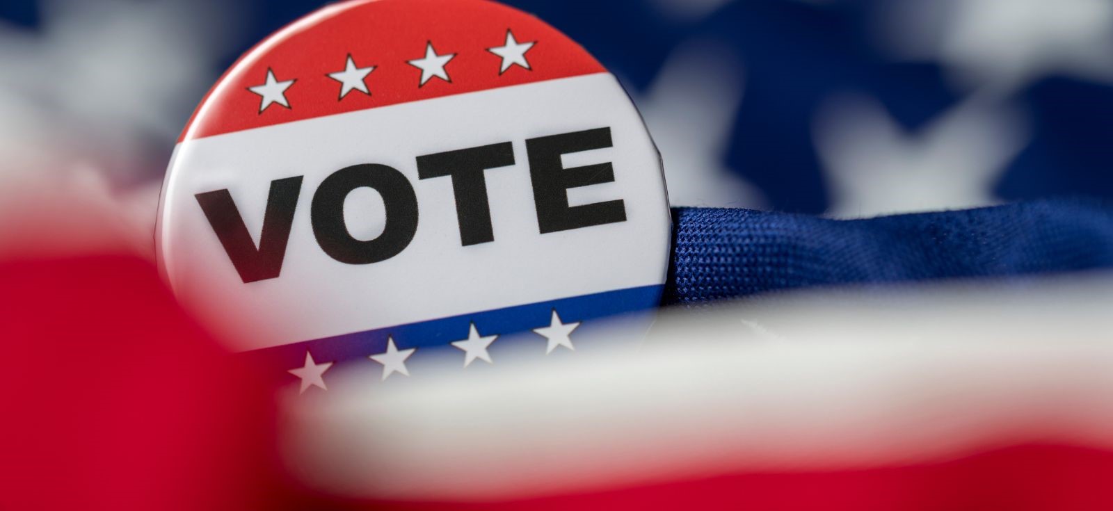 Large button that says VOTE tucked among blue and red fabric