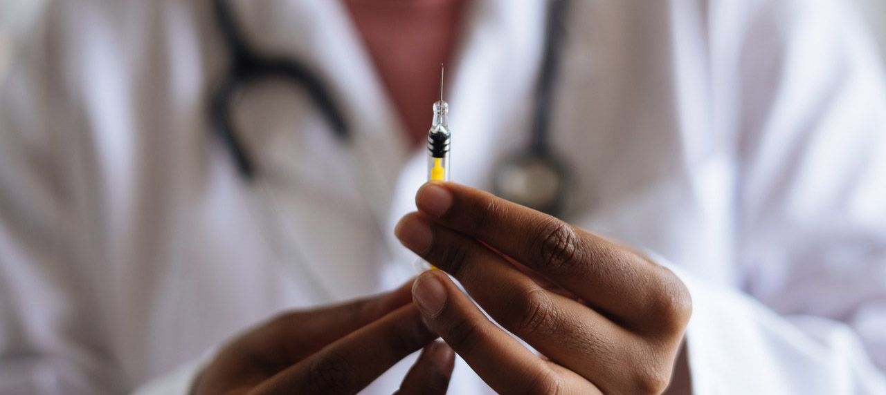 Picture of a doctor's hands holding a vaccine in front of the camera